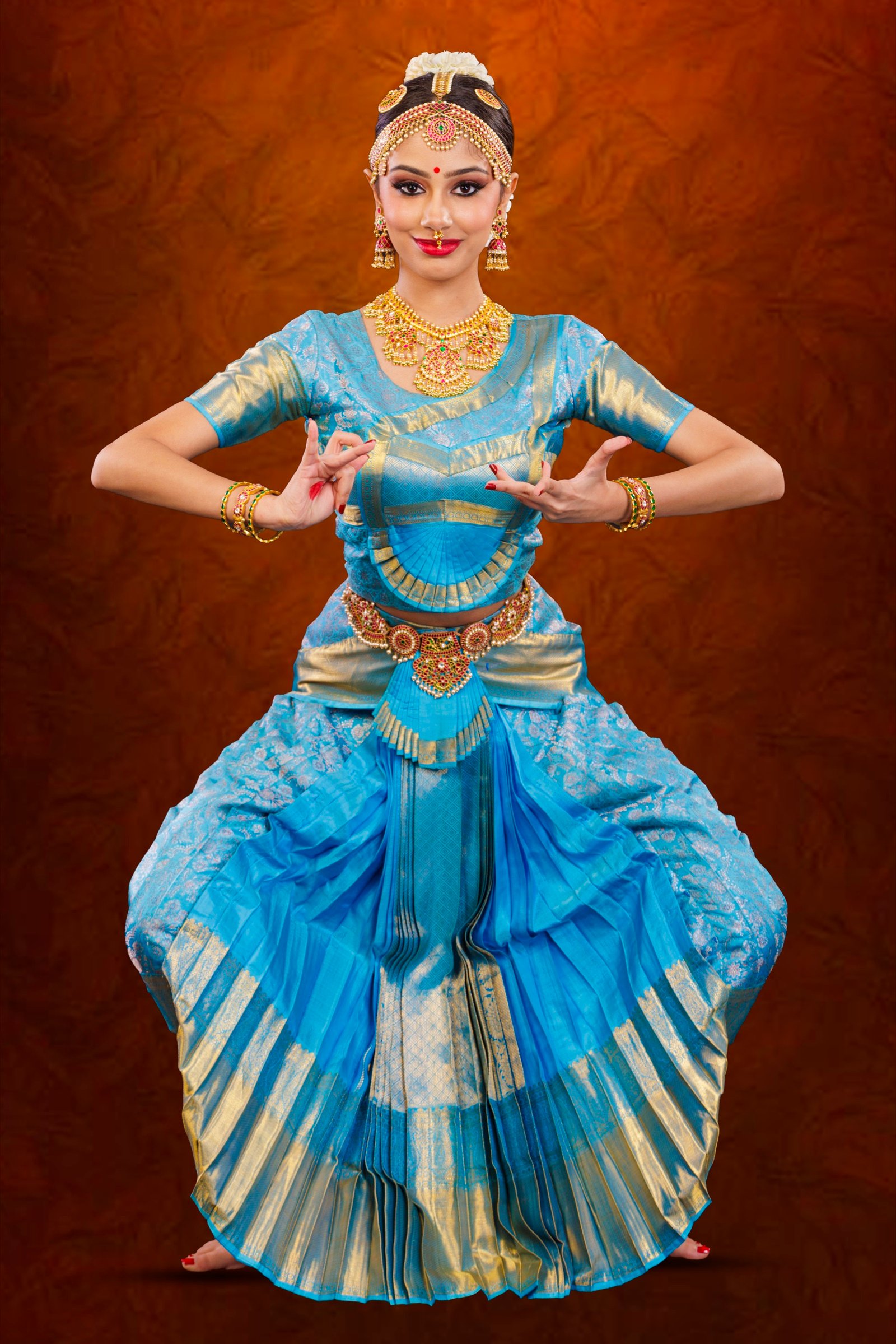 Ilesha in a symmetric half-seated stance, skirt pleats fanned wide